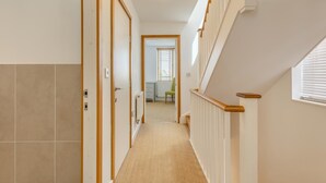 A hallway with a carpeted floor, a radiator, a door, and a window with blinds. - 2 Bed in Southwold (oc-ftw2) (Southwold)