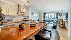 Een moderne keuken met een centraal eiland, een zithoek met een bank, en uitzicht op een kerk door het raam.