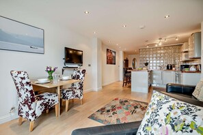 A modern living room with a dining area, a kitchen, and a TV mounted on the wall. - 1 Bed in St. Ives (oc-f27573) (St Ives)