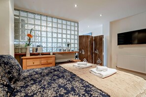 Ein Schlafzimmer mit einem großen Bett, einer Holzkommode, einem Schminktisch, einem Spiegel, einem Fernseher und einem großen Fenster mit Blick.