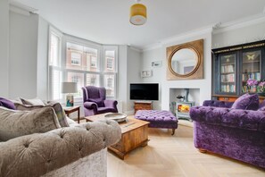 A modern living room with a fireplace, comfortable seating, and a television. - 3 Bed in Southwold (oc-tlw2) (Southwold)