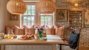 A cozy dining area with a wooden table set for breakfast, featuring pastries, fruits, and a vase of flowers. - 3 Bed in Wittersham (oc-m27683) (Wittersham)