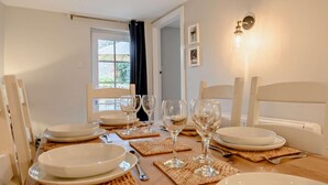 A dining table set with plates, glasses, and cutlery, with a view of a garden through a window. - 3 Bed in Wiveton (oc-d19479) (Wiveton)
