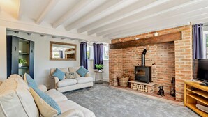 A cozy living room with a fireplace, a sofa, a television, and a bookshelf. - 3 Bed in Tholthorpe (oc-r23426) (Tholthorpe)