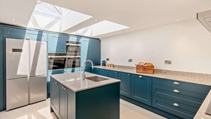 A modern kitchen with blue cabinets, a stainless steel refrigerator, and a skylight. - 3 Bed in Tholthorpe (oc-r23426) (Tholthorpe)