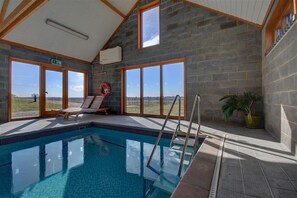 Ein Innenpool mit freiem Blick ins Freie, ein Rettungsschwimmerstuhl und ein Blumentopf.