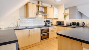 Een moderne keuken met houten kastjes, een roestvrijstalen afzuigkap en een zwart aanrecht.