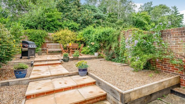 A backyard with a barbecue grill, wooden deck, potted plants, and a brick wall. - 3 Bed in Wrentham (oc-m6144) (Wrentham)