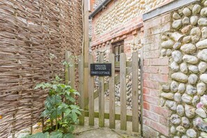 Un portail d’entrée privé menant à un jardin, sur lequel est apposée une plaque indiquant : « JARDIN PRIVÉ – DINKY COTTAGE ».