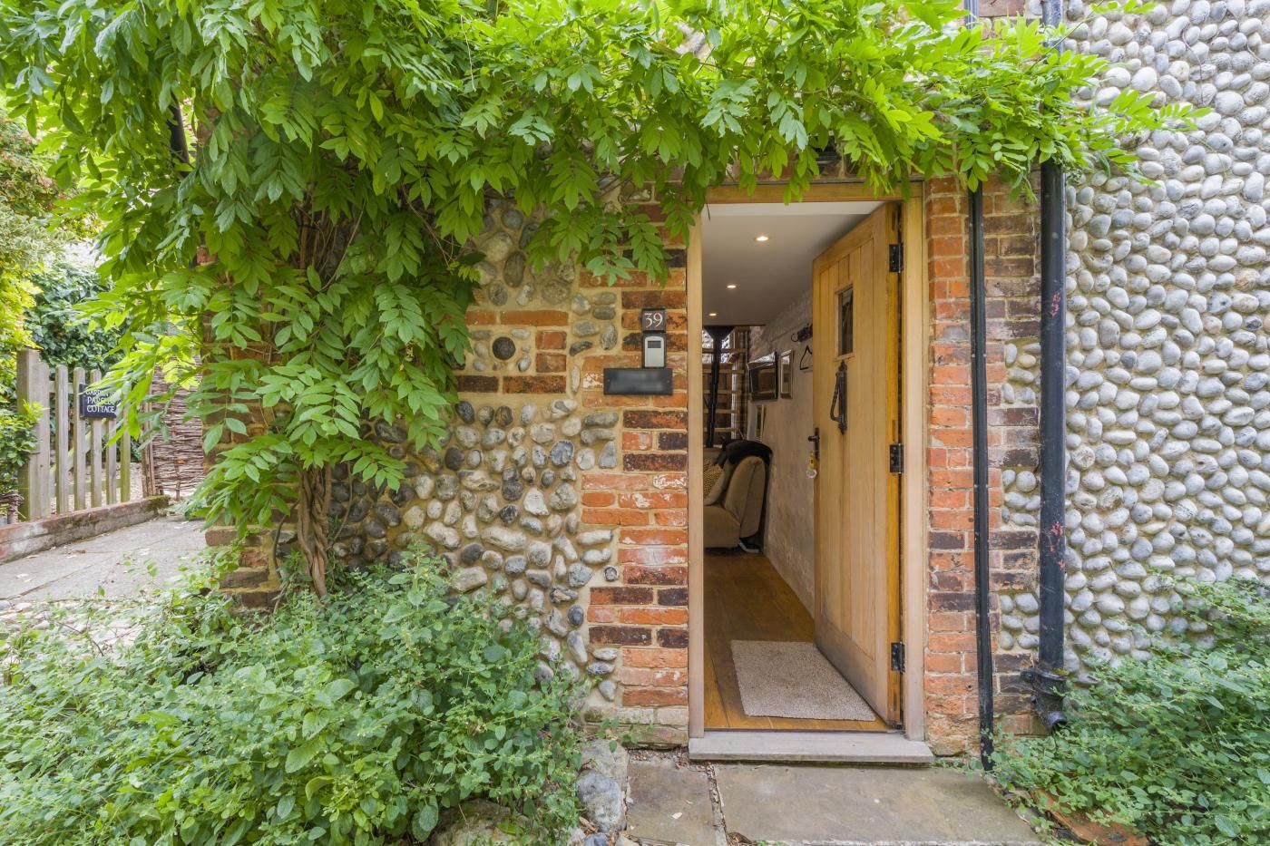 A rustic cottage entrance with a stone wall, wooden door, and a small porch area.