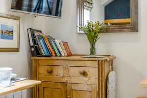 Un meuble en bois contenant des livres, un vase avec des fleurs, un téléviseur et un tableau encadré accroché au mur.