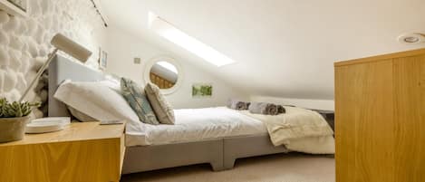 A compact bedroom with a bunk bed, a desk, a potted plant, and a round mirror.