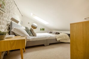 Habitació compacta amb llit superposat, escriptori, una planta en test i un mirall rodó.
