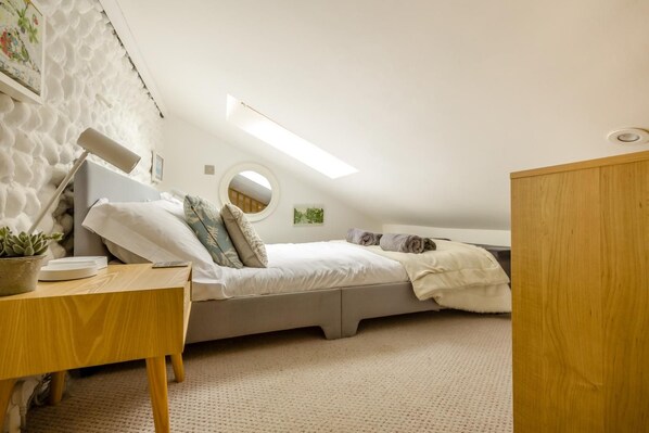 Une chambre à coucher de taille réduite, avec un lit superposé, un bureau, une plante en pot et un miroir rond.