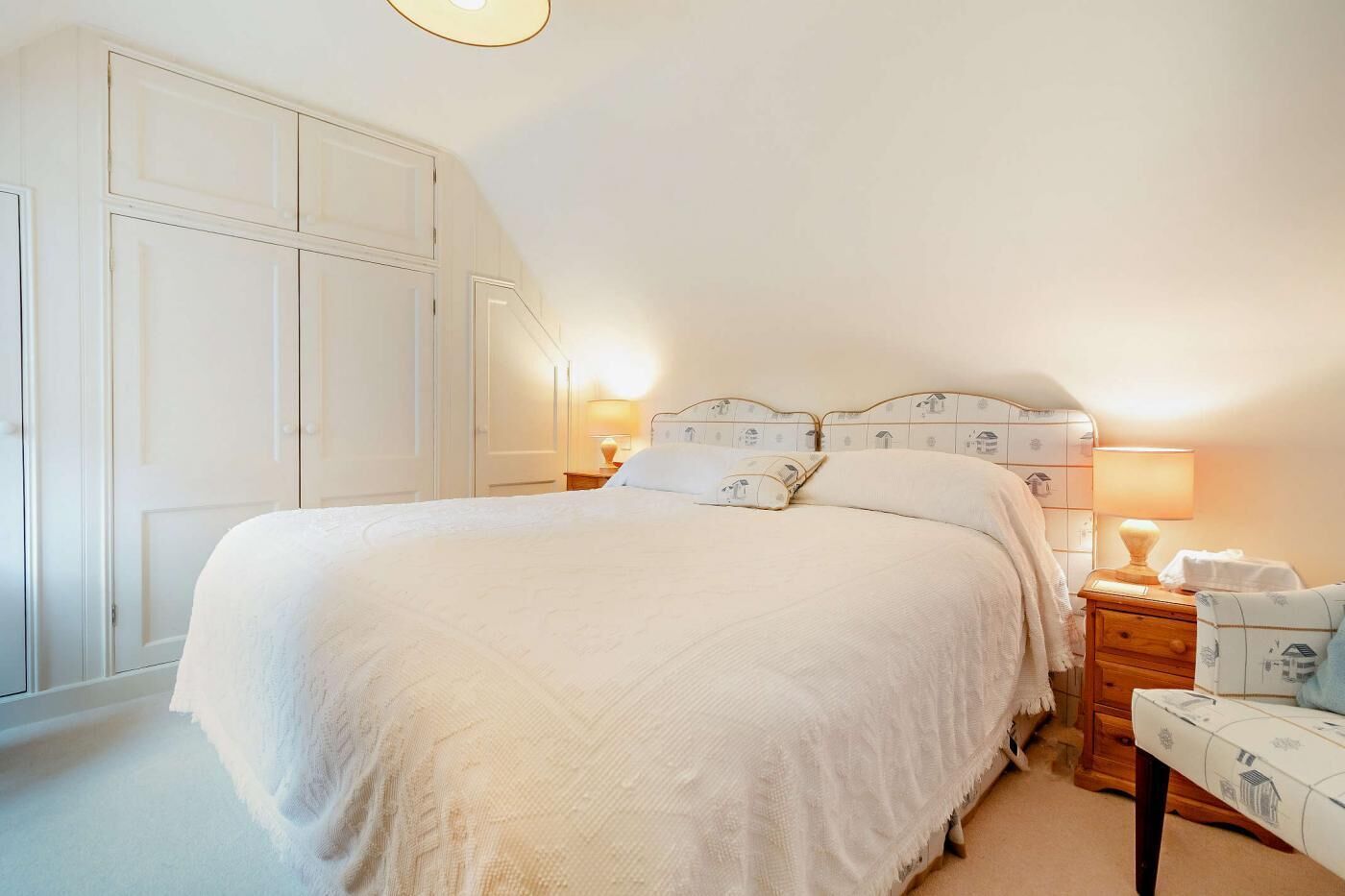Een keurig opgemaakte slaapkamer met een groot bed, nachtkastjes en een kledingkast.