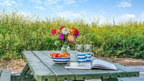 Ein Picknicktisch mit Obstschale, Blumenstrauß und zwei Gläsern auf einem Buch.