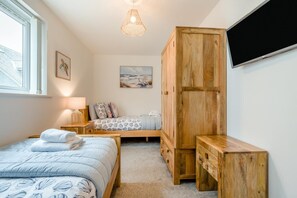 Ein Schlafzimmer mit einem Bett, einem Holzschrank, einer Bank, einem Schreibtisch, einer Lampe und einem Bild an der Wand.