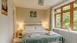 Une chambre à coucher avec un lit, des lampes de chevet, une fenêtre donnant sur un beau paysage et un luminaire suspendu.