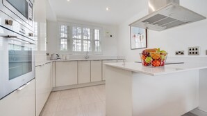 A modern kitchen with white cabinetry, a built-in oven, and a fruit basket on the counter. - 1 Bed in Saundersfoot (oc-pw927a) (Saundersfoot)