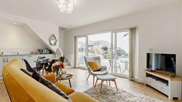 A modern living room with a sofa, a TV, and a dining area with a table and chairs.