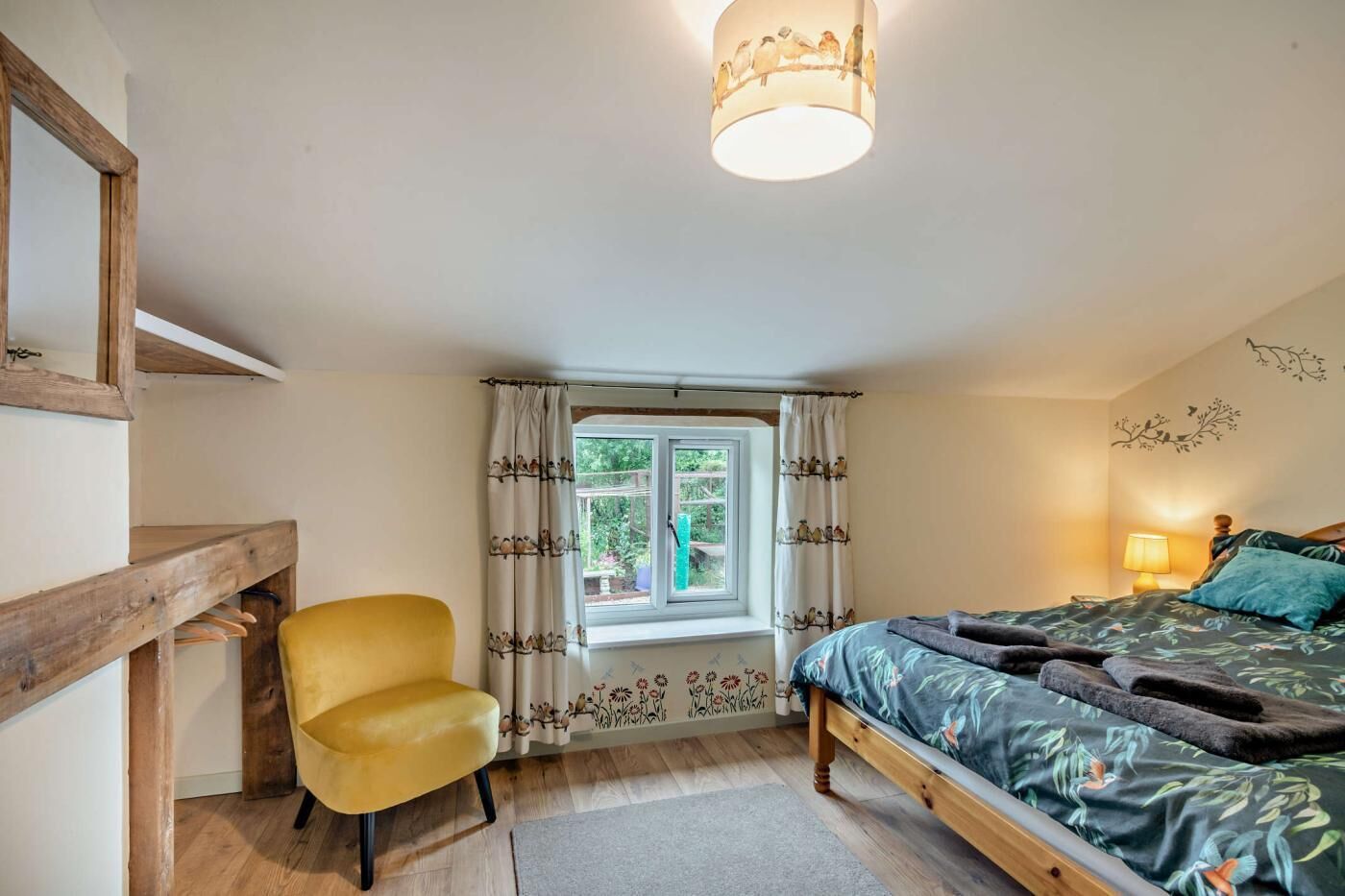 A bedroom with a bed, a chair, a window with curtains, and a lamp.