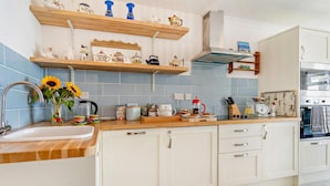 Une cuisine avec des meubles blancs, un plan de travail en bois et des carreaux bleus.