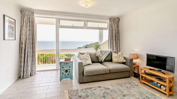 Un salon avec un canapé, une télévision et une vue sur la mer.