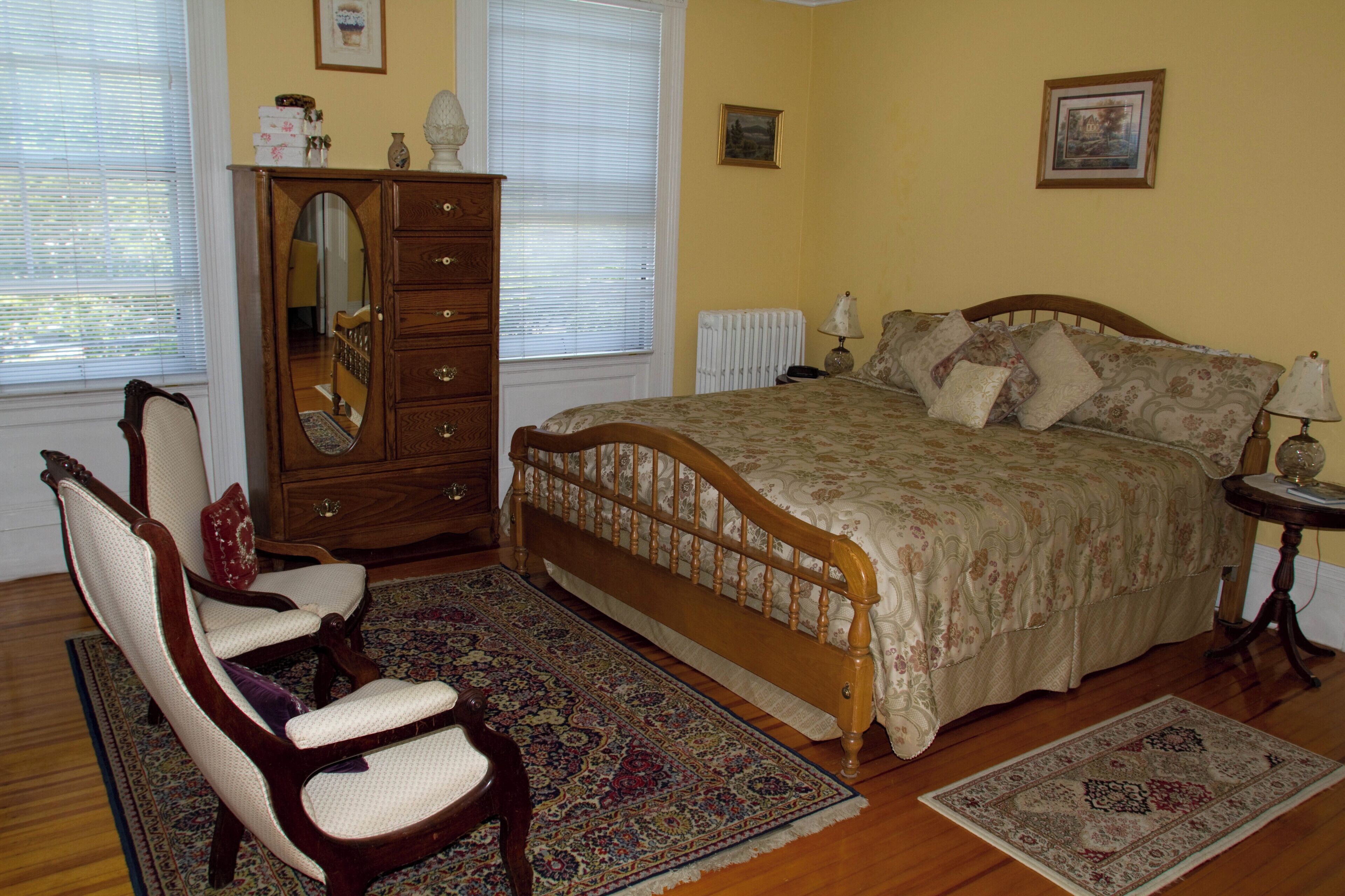 A bedroom with a wooden bed, a dresser, a chair, and a rug.