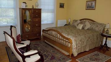 A bedroom with a wooden bed, a dresser, a chair, and a rug.
