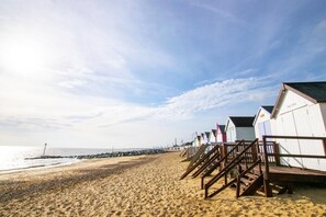 A beach with wooden walkways leading to beach huts. - 3 Bed in Felixstowe (oc-s27808) (Felixstowe)