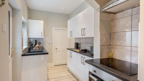 Une cuisine moderne avec des meubles blancs, un plan de travail noir et une hotte en acier inoxydable.