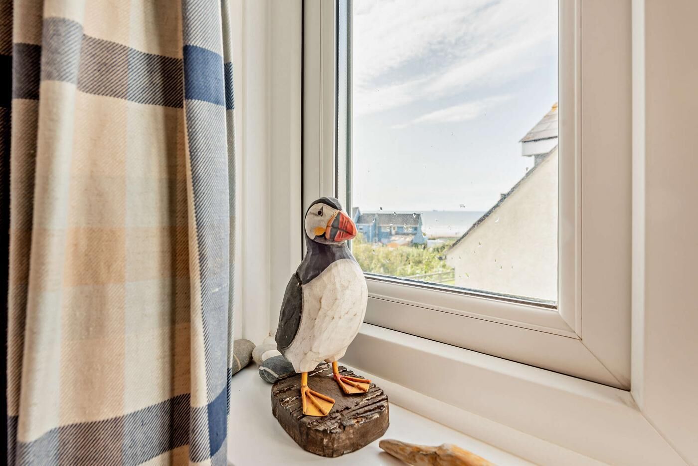 A pufferfish figurine on a wooden base by a window with a view of buildings and a cloudy sky.