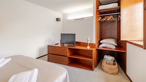 A bedroom with a bed, a TV, wooden furniture, a closet, and a small basket. - Waterfront House · Gerês (Gerês)