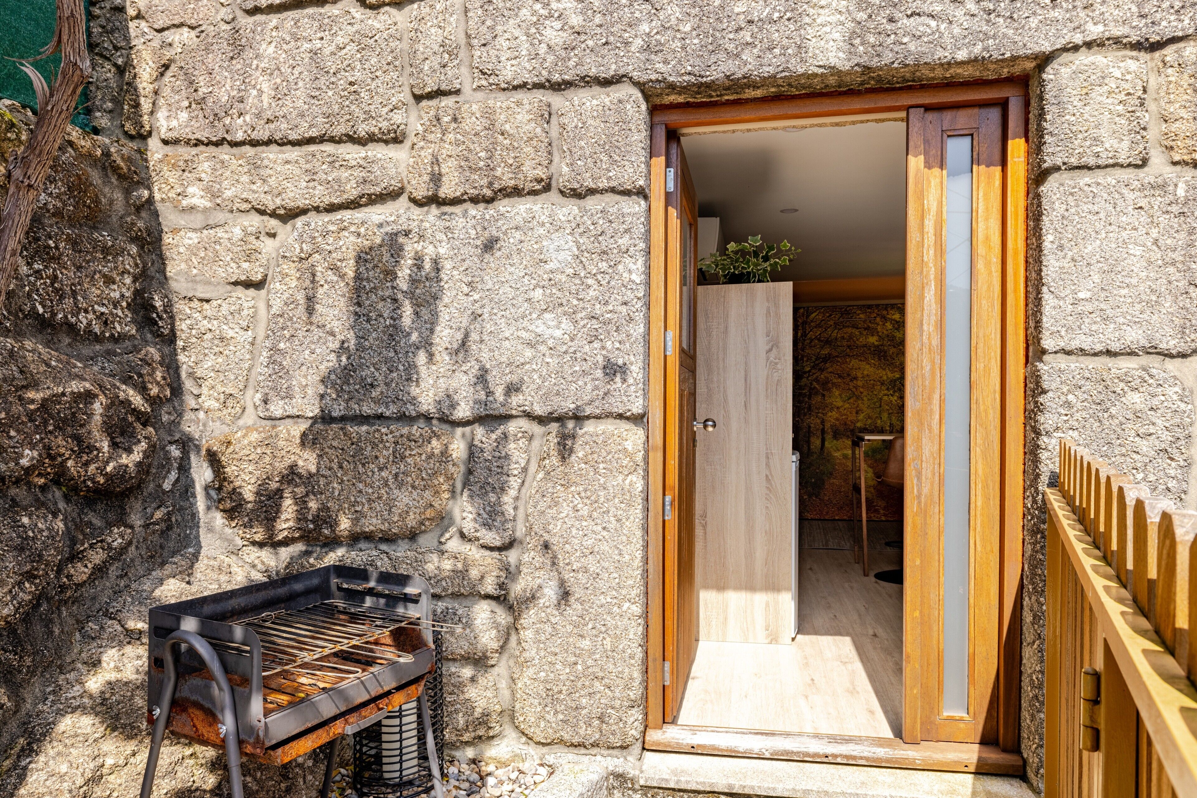 A stone building with a wooden door and a grill outside.
