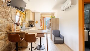 A modern kitchen with a stone wall, a flat-screen TV, and a bar area with stools.