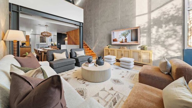 Ein modernes Wohnzimmer mit einer Sofagarnitur, einem Couchtisch und einem an der Wand befestigten Fernseher.