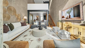 Ein modernes Wohnzimmer mit einer Couch, einem Couchtisch und einem Fernseher auf einer Holzkommode.
