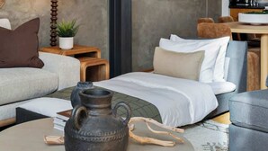 Ein modernes Schlafzimmer mit einem Bett, einem runden Couchtisch, einer Topfpflanze und einem Holznachttisch.