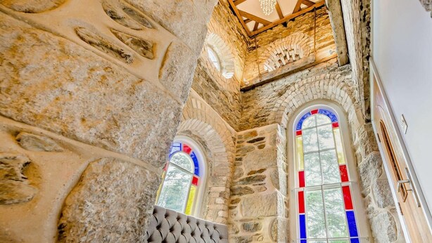 Un interior de piedra con ventanas de arco y techo de madera.