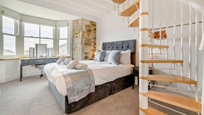 Un dormitorio con cama, escritorio y una escalera de caracol.