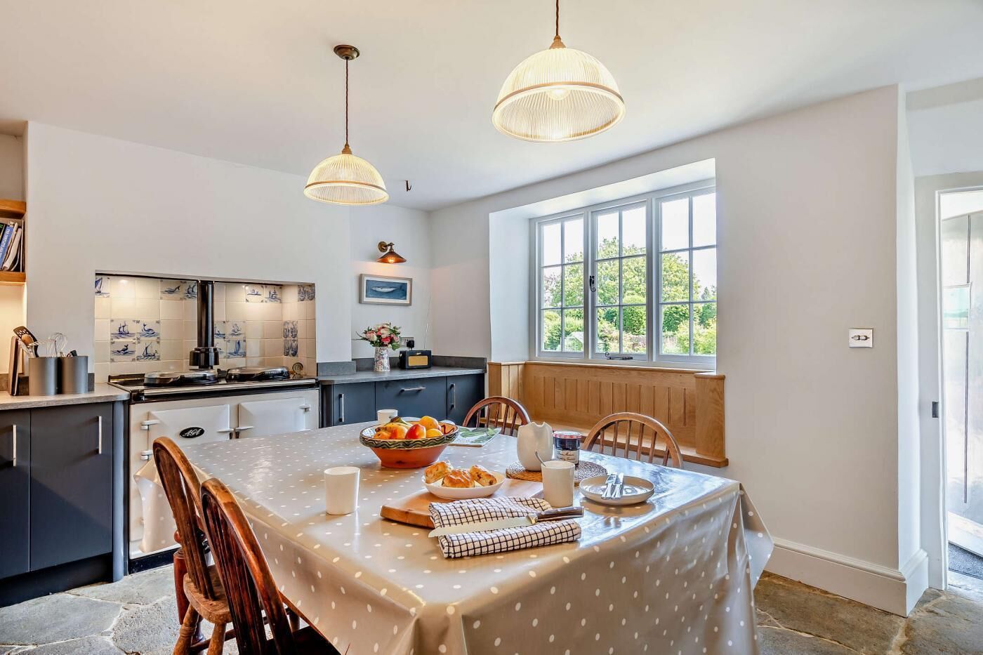 A modern kitchen with a large island, a dining area with a table set for four, and a large window providing natural light.