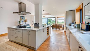 A modern kitchen with a central island, built-in cabinets, and a large window providing natural light. - 5 Bed in Rye (oc-o27820) (Rye)