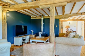 A living room with a TV, wooden beams, a sofa, and a table with a vase. - 3 Bed in Ellough (oc-b5208) (Ellough)
