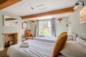 A bedroom with two beds, a fireplace, a chair, and a window with curtains. - 13 Bed in Ellough (oc-m11311) (Ellough)