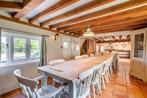 A long wooden dining table with white chairs, a kitchen area with a heart-shaped decoration, and a staircase leading to another level. - 13 Bed in Ellough (oc-m11311) (Ellough)