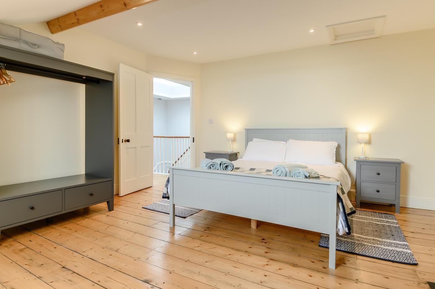 A bedroom with a bed, bedside tables, a desk, and a wardrobe.