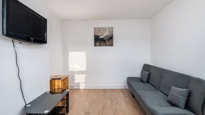 A modern living room with a flat-screen TV, a gray sofa, and a wooden cabinet.