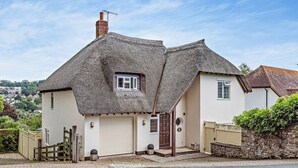 Een huis met twee verdiepingen, een rieten dak, een garage en een stenen muur.