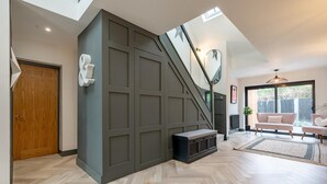 Ein modernes Interieur mit Fischgratschichtboden, einer Treppe an einer dunklen Wand und einem Wohnbereich mit Sofa und Couchtisch.