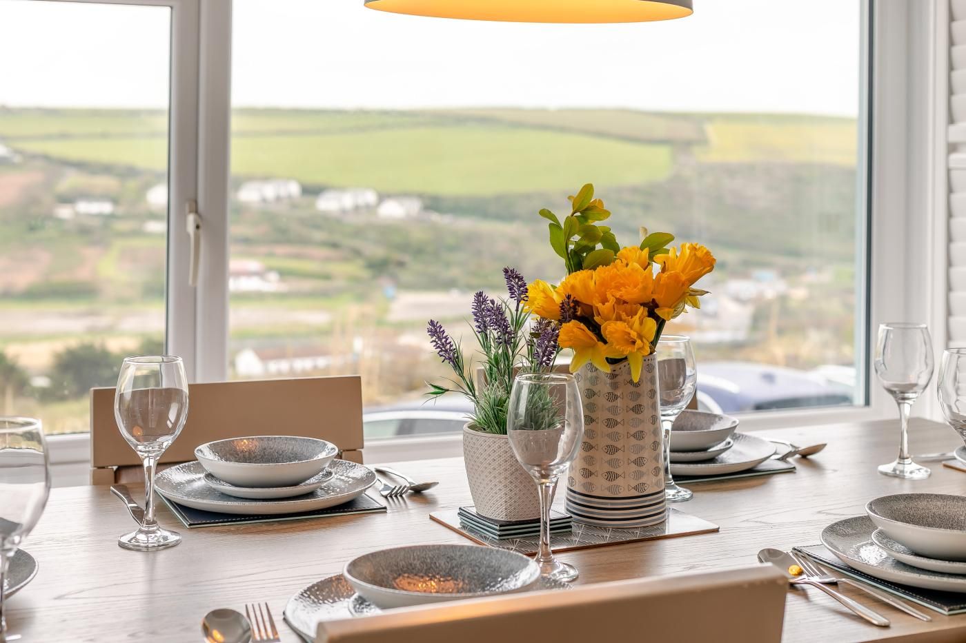 Une table à manger dressée pour deux personnes, avec vue sur la campagne.